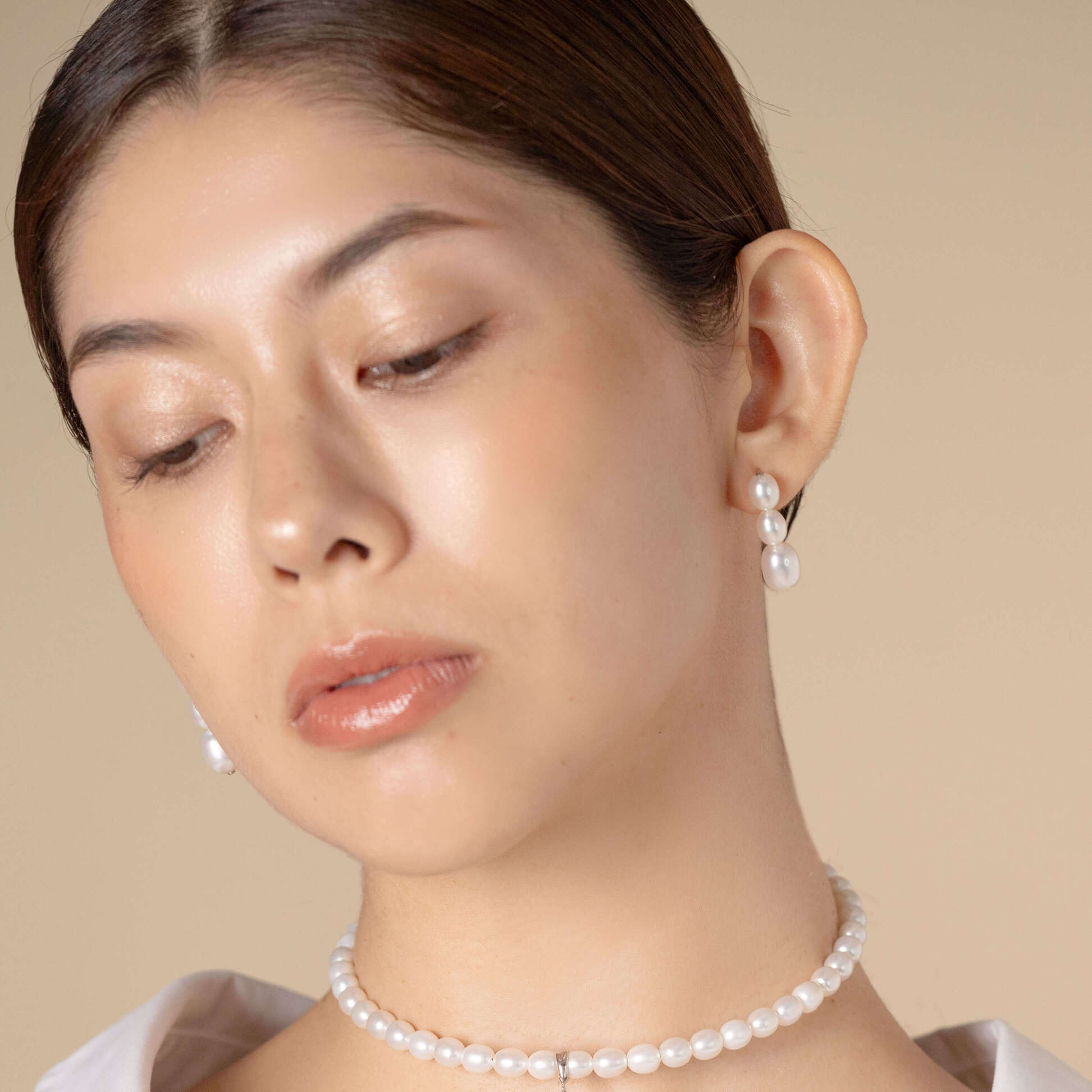 Elevate your look with a sophisticated black top and stunning pearl earrings on a woman. Timeless and classy!