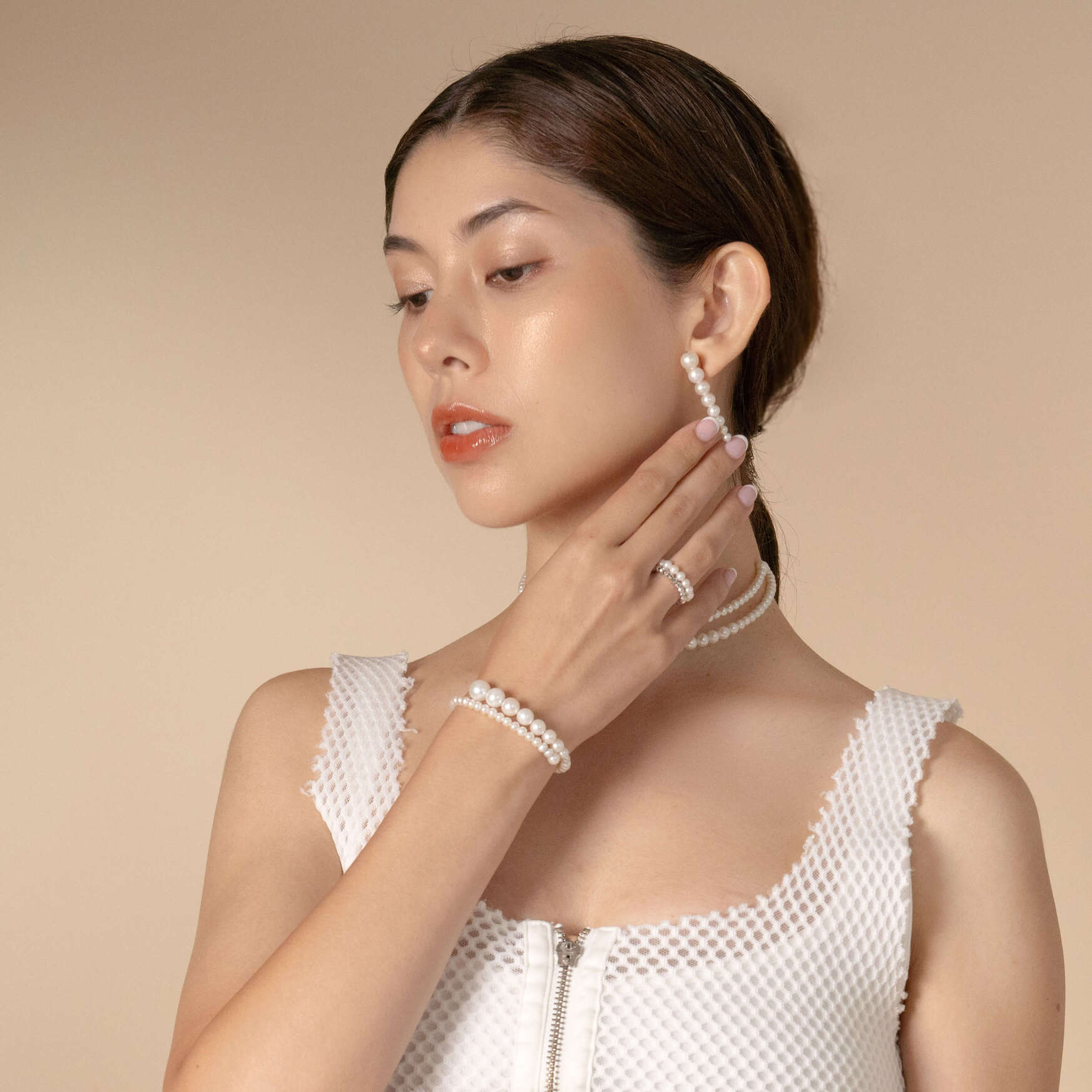 Sophisticated woman wearing white top and pearl necklace, enhanced by a beautiful spiral pearl bracelet.