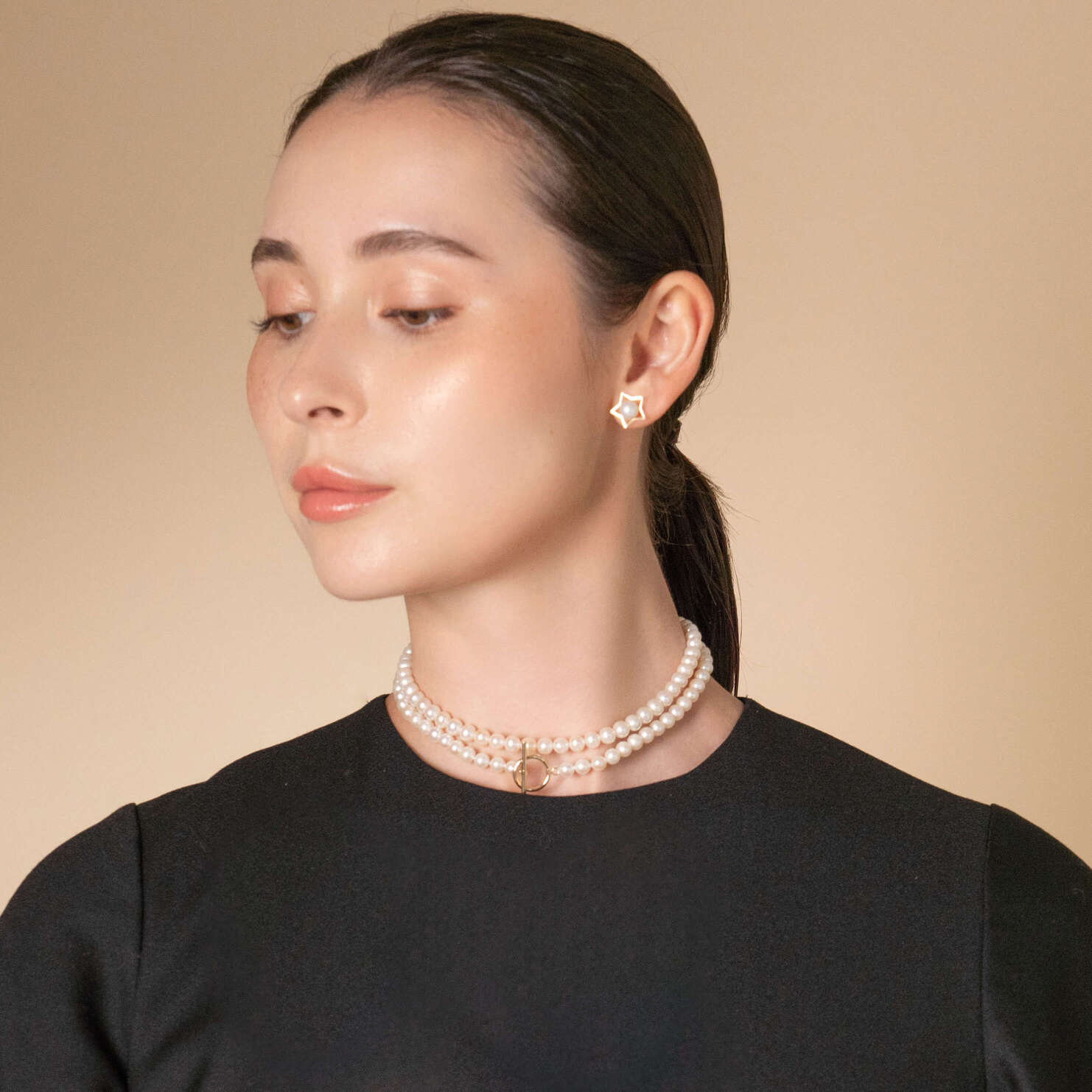 Embrace elegance with a woman donning a black top and a mesmerizing Mantel Pearl Necklace. Perfect for any occasion!