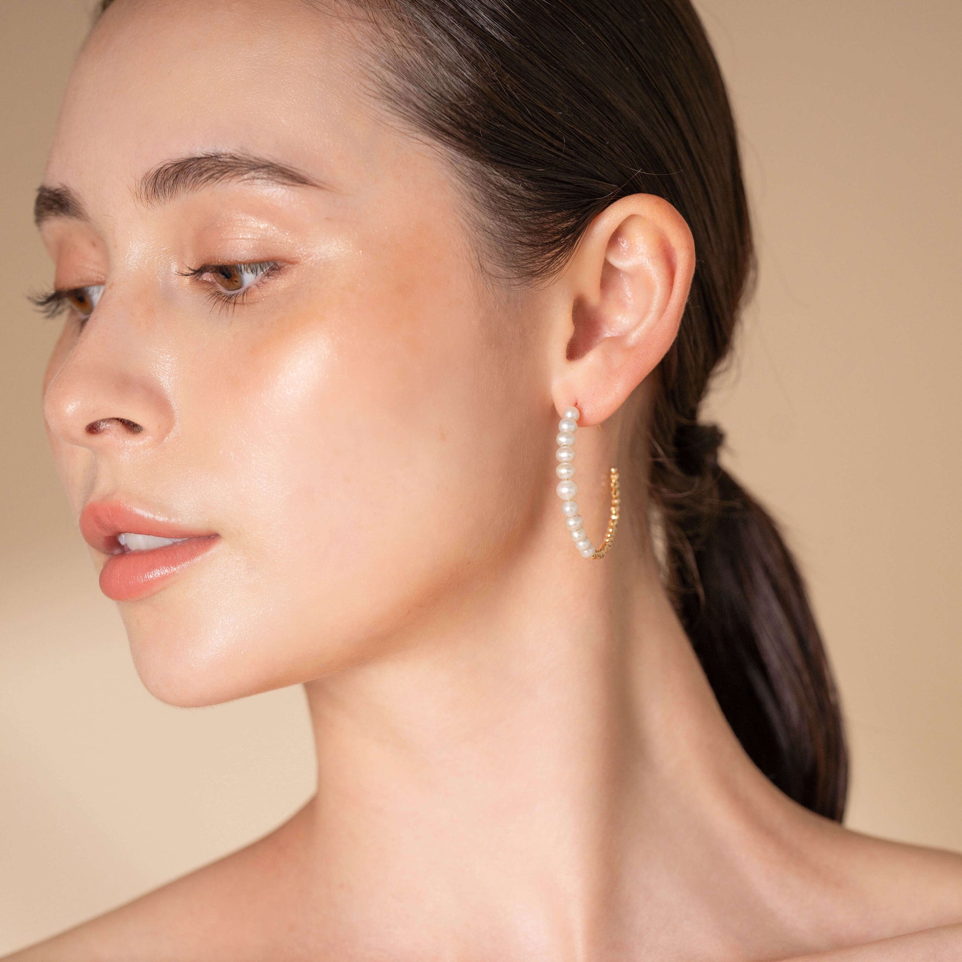 Chic woman in white top accessorized with Mirror Gold x Pearl Hoop Pierce earrings.