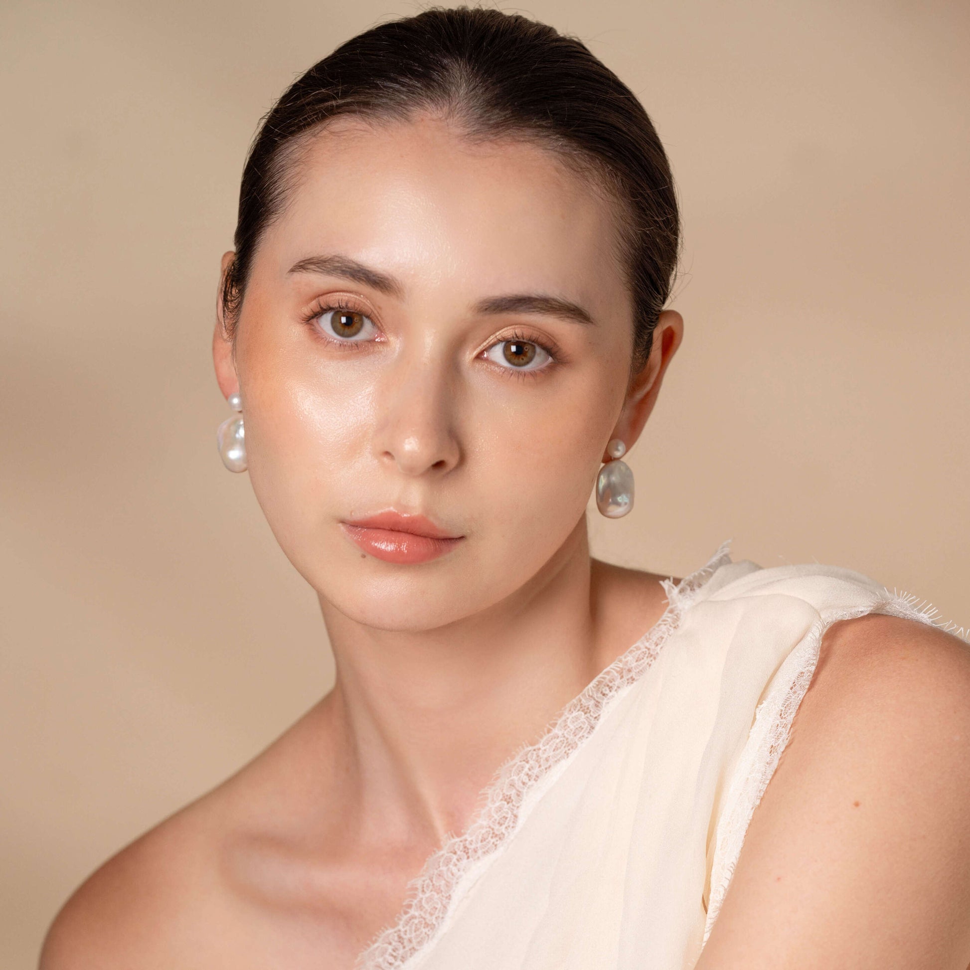 Stylish woman wearing white dress and earrings, with a Baroque Pearl Charm Piercing.