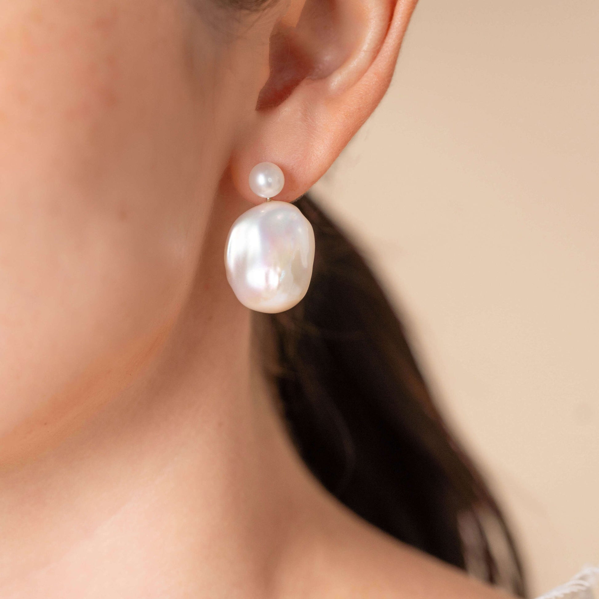Enhance your style with a Baroque Pearl Charm Piercing worn by a woman with a pearl earring.