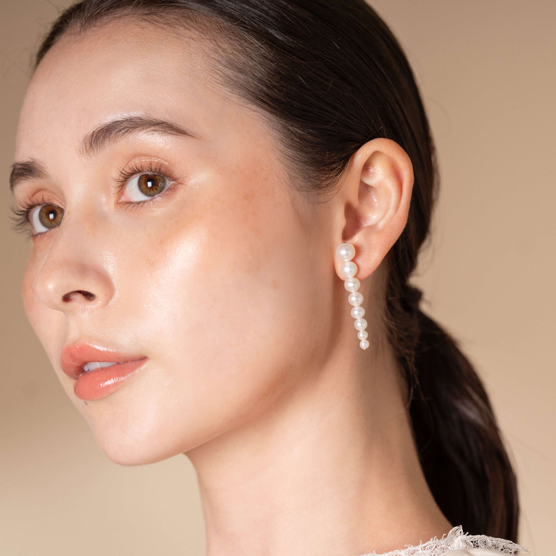 Discover the allure of Stella Piercing: a woman captivating in a white dress and stunning earrings.