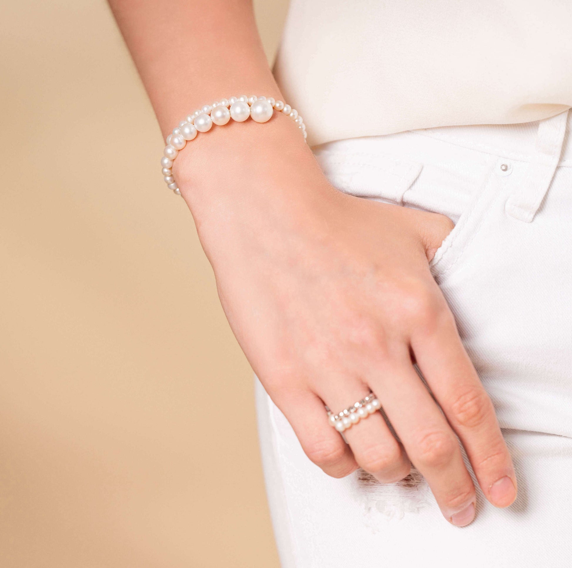 Stylish woman in white jeans accessorized with a chic Spiral Pearl Bracelet.