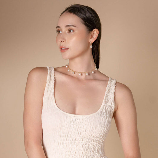 Enhance your style with a stunning woman in a white dress and a Pearl Dot x Gold Choker necklace.
