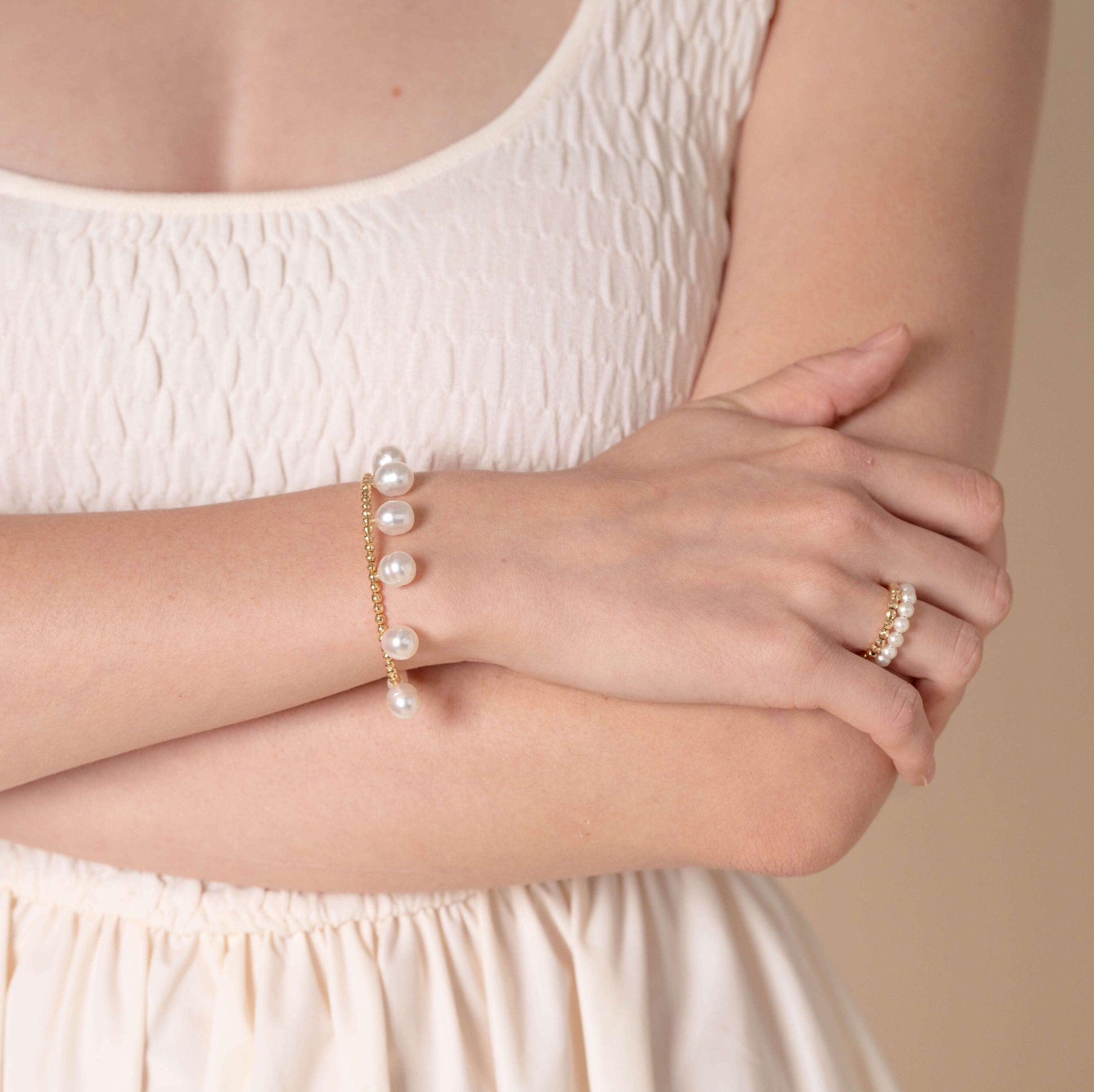 Stylish lady in white dress accessorized with Pearl Dot x Gold Bracelet.