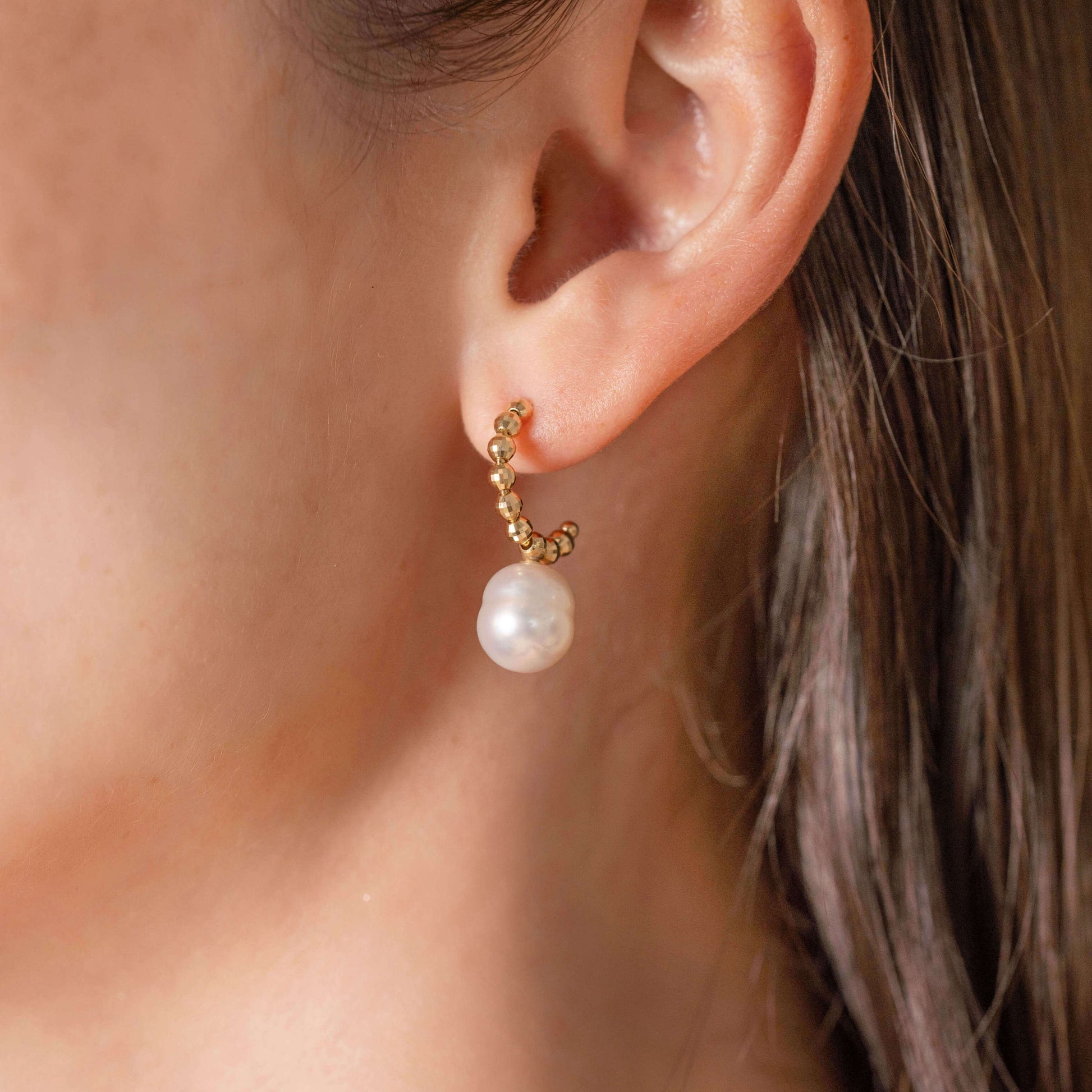Indulge in sophistication as you admire a woman donning a pearl necklace and earrings. Embrace the allure of Pearl Dot x Gold Piercing for a touch of timeless elegance.