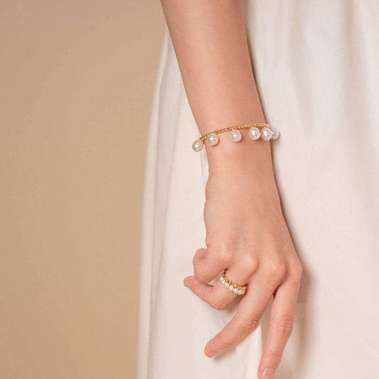 Elegant woman in white dress with Pearl Dot x Gold Bracelet.