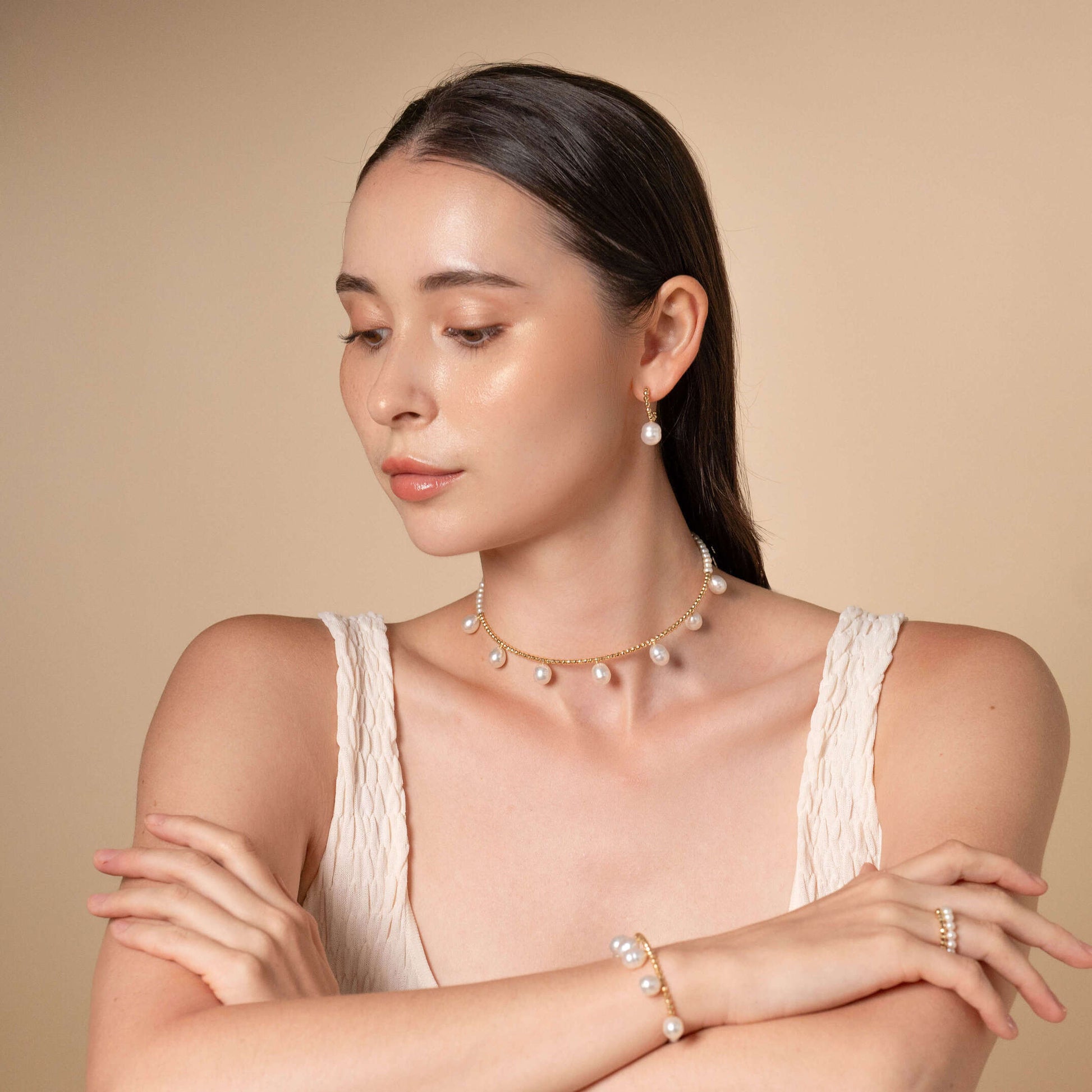 Embrace sophistication with a woman in a white dress adorned with a Pearl Dot x Gold Choker necklace.