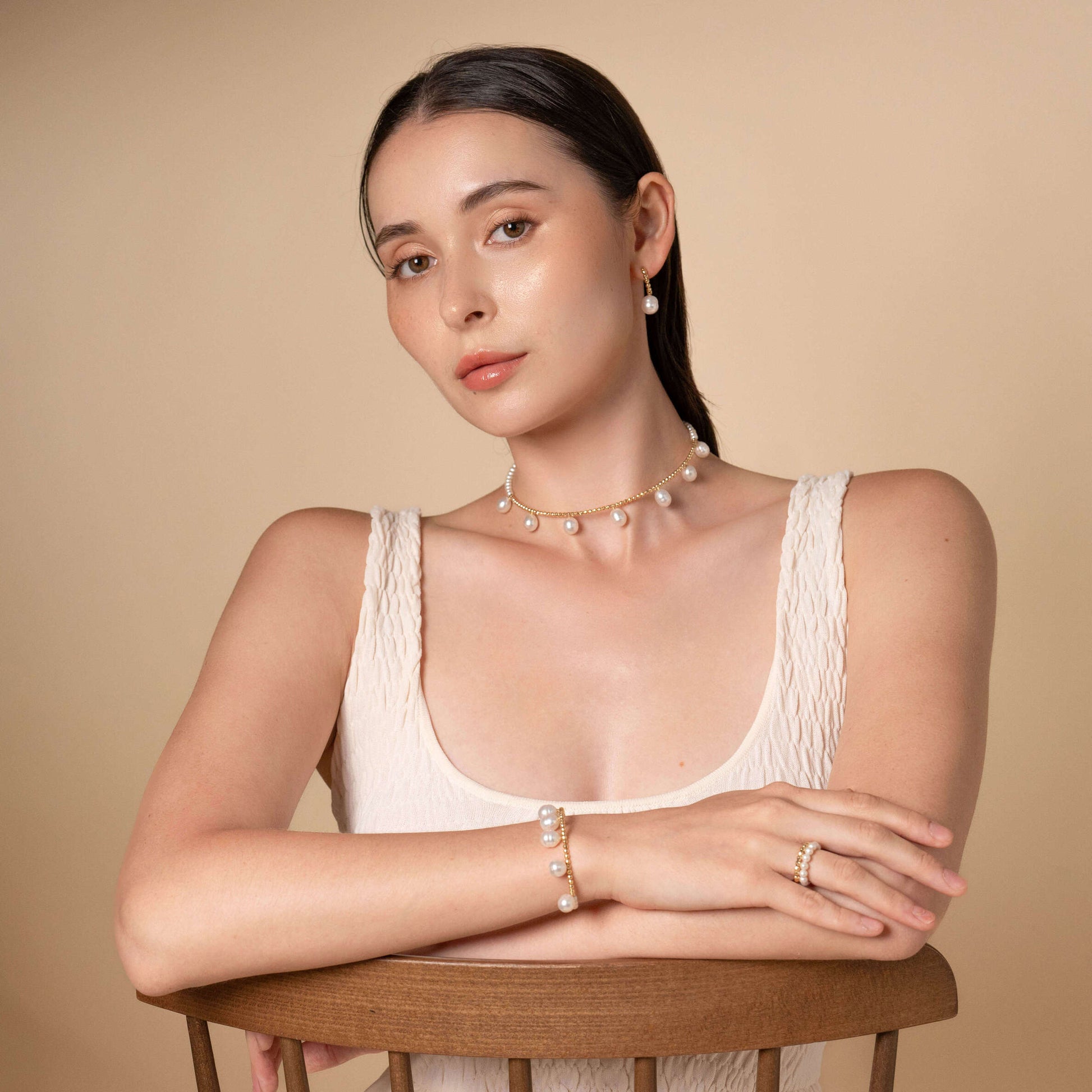 Elevate your elegance with a woman in a white dress and a Pearl Dot x Gold Choker necklace.