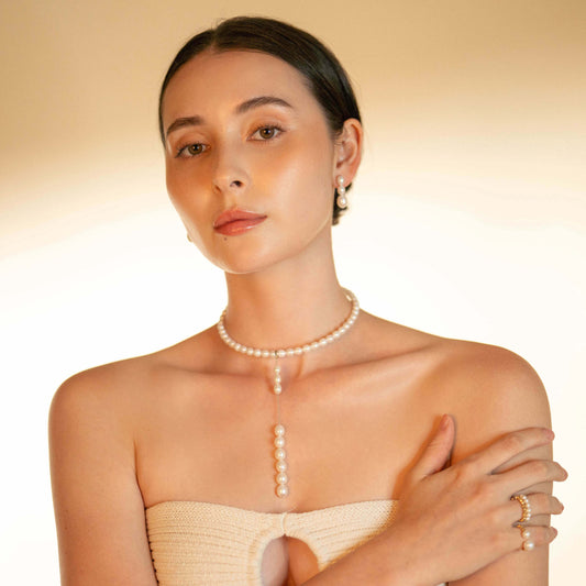 Elegant woman in white dress accessorized with Oval Pearl Charm Choker.