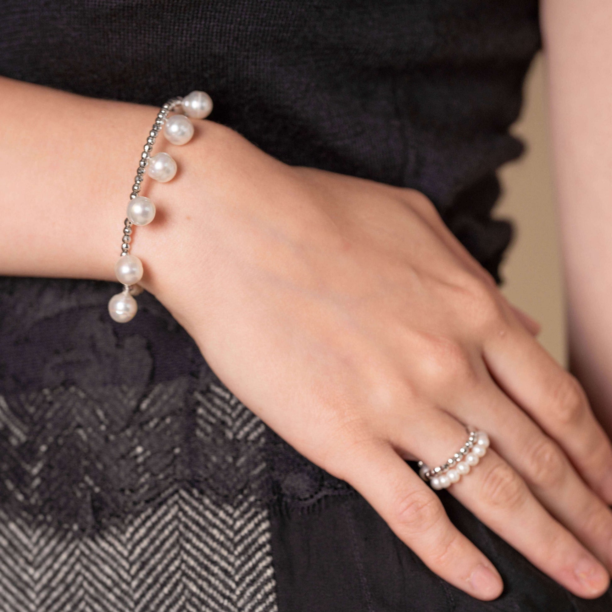 Enhance your style with a woman wearing a silver bracelet and a Pearl Dot x White Gold Bracelet.
