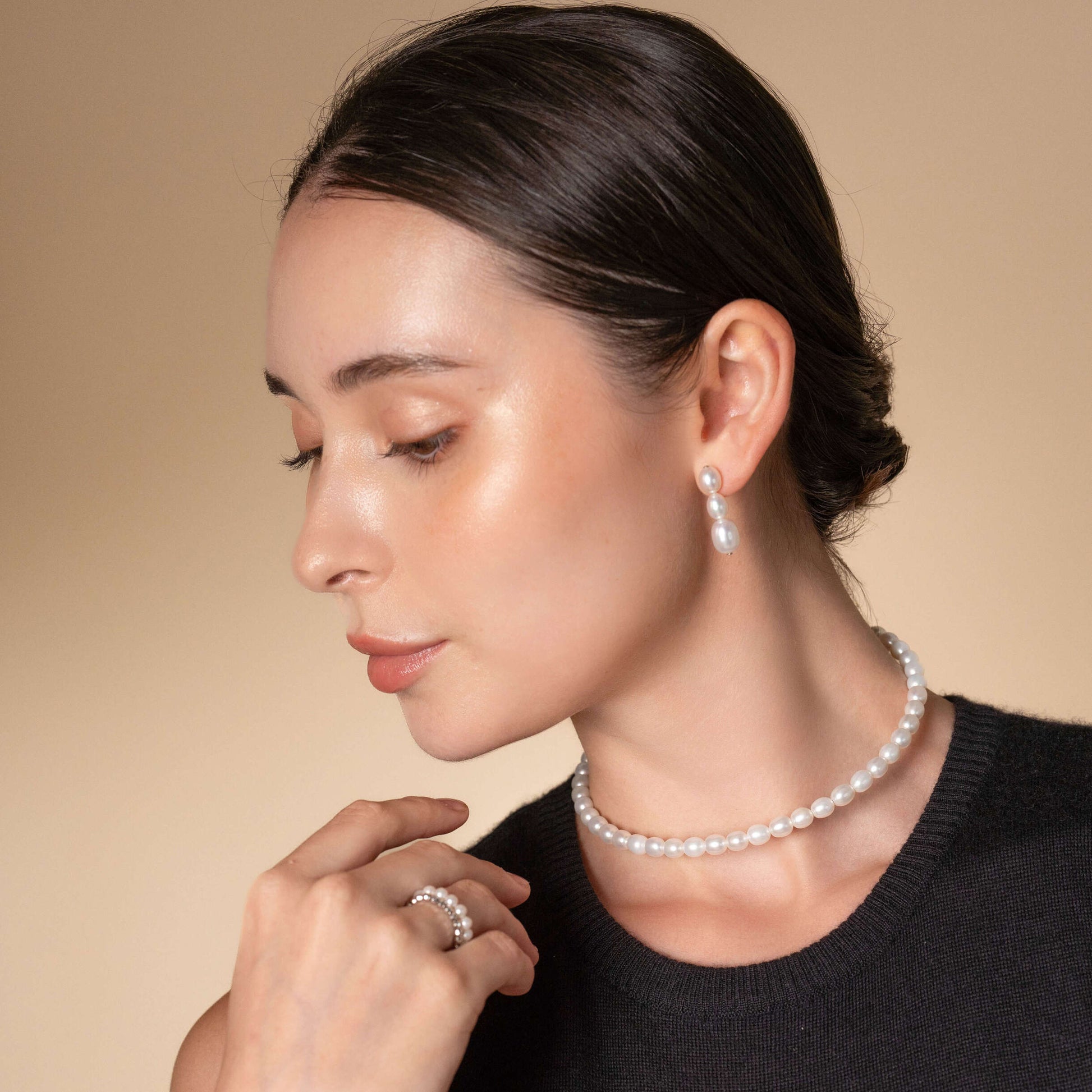 Discover timeless beauty as a woman showcases her sophistication with a pearl necklace and earrings. Complete your ensemble with an alluring Oval Pearl Charm Choker.
