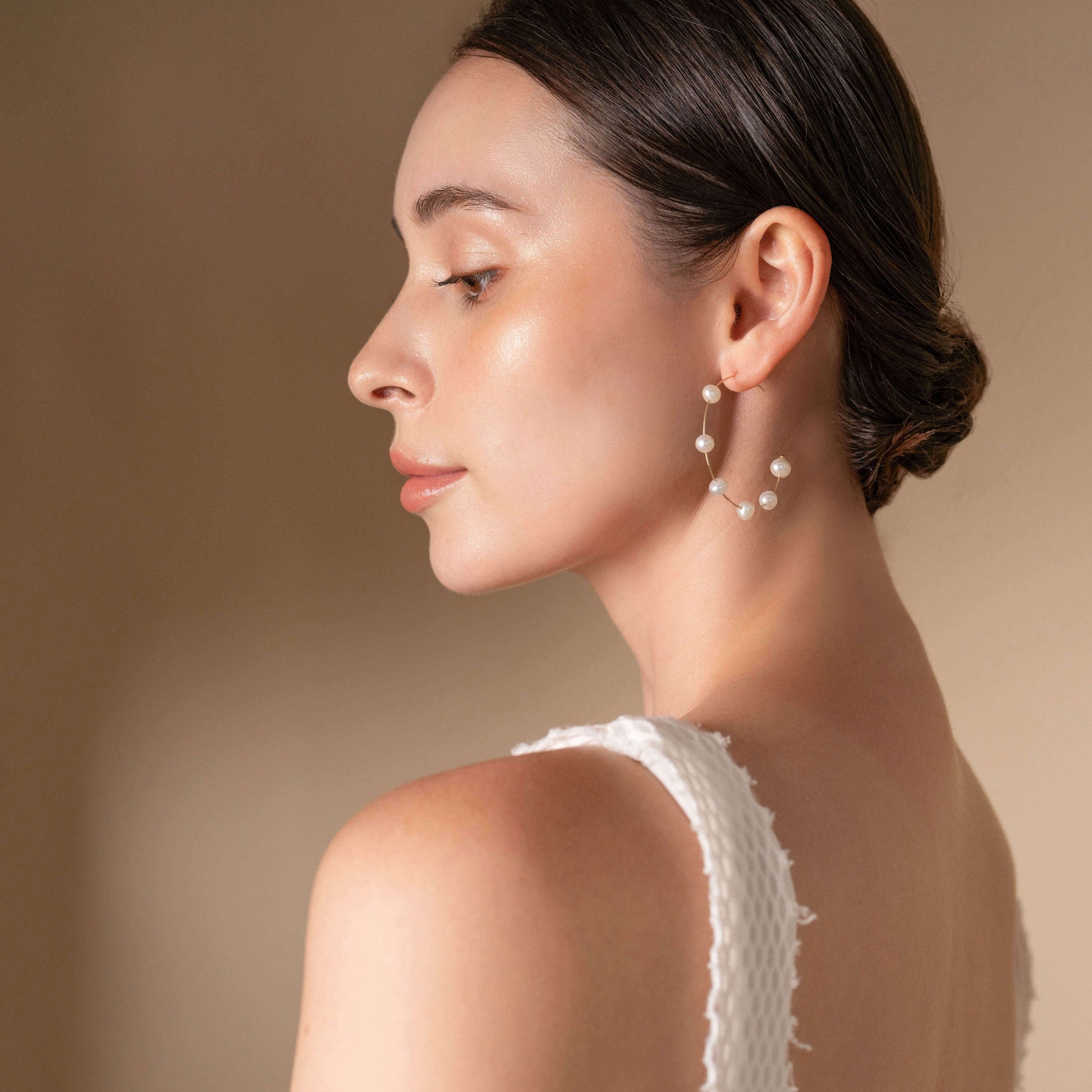 Enhance your look with a white top and Dot Pearl Hoop Piercing earrings like this woman.