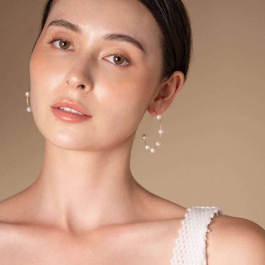 Stylish woman in white top and Dot Pearl Hoop Piercing earrings exudes elegance.