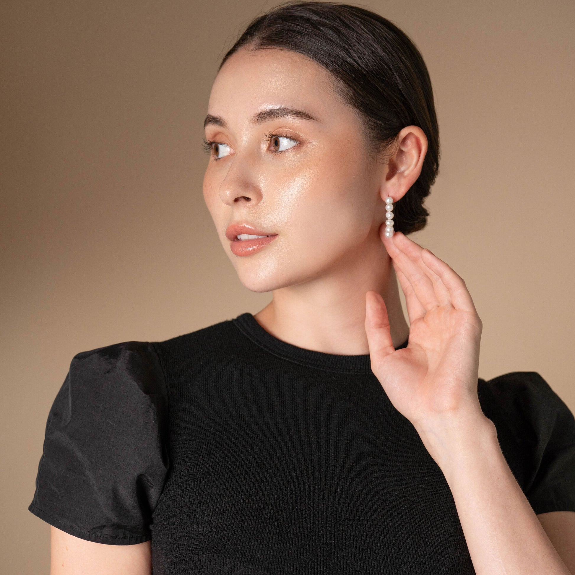 Embrace sophistication with a woman wearing a black top and captivating earrings.