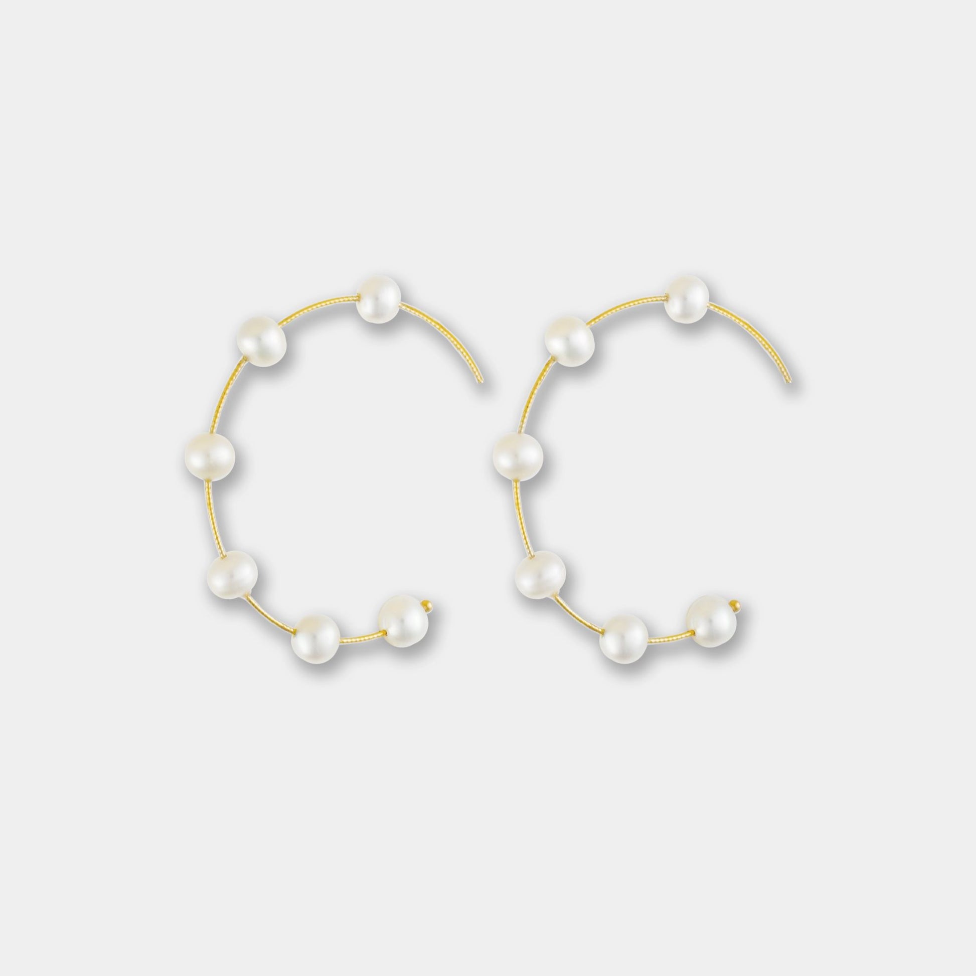 Embrace sophistication with these captivating gold hoop earrings embellished with delicate white pearls. A must-have for any jewelry collection.