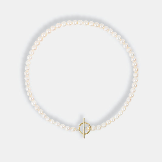 A Mantel Pearl Necklace Short with a gold clasp and a dainty pearl, elegantly adorning a pearl bracelet.