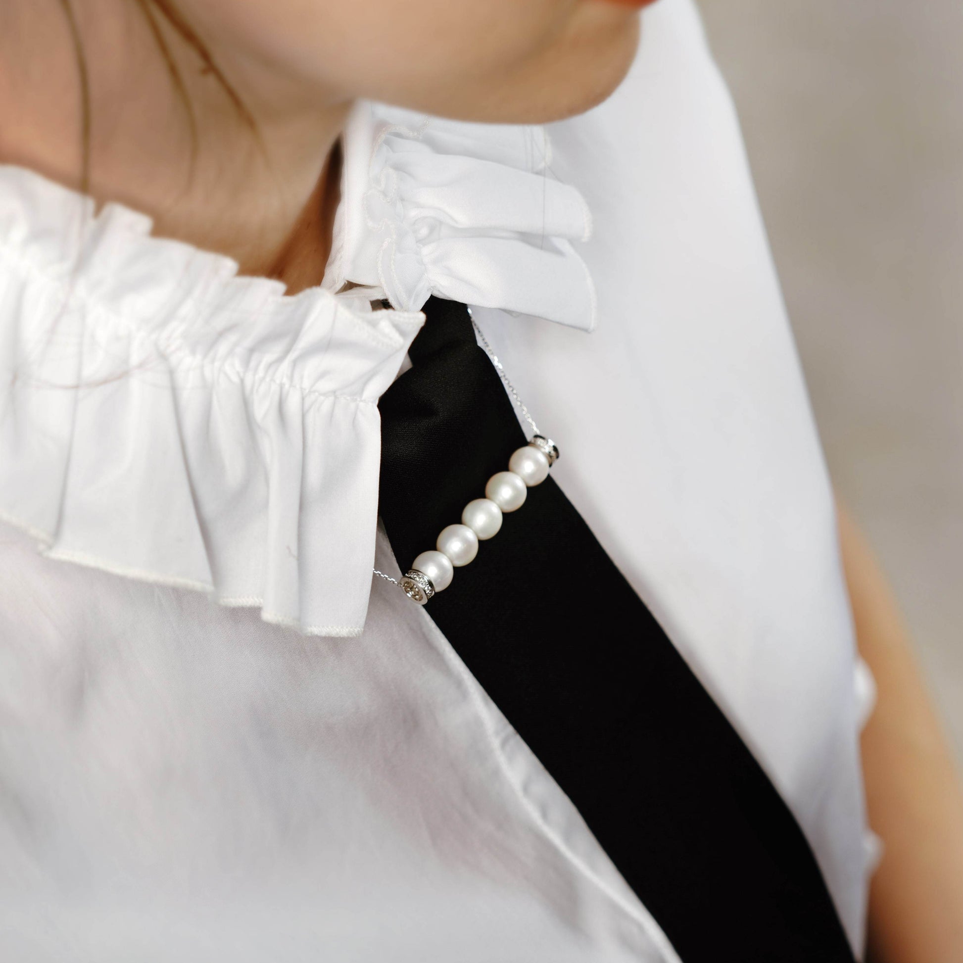 Chic woman wearing white shirt and stunning Parallel Pearl Necklace.