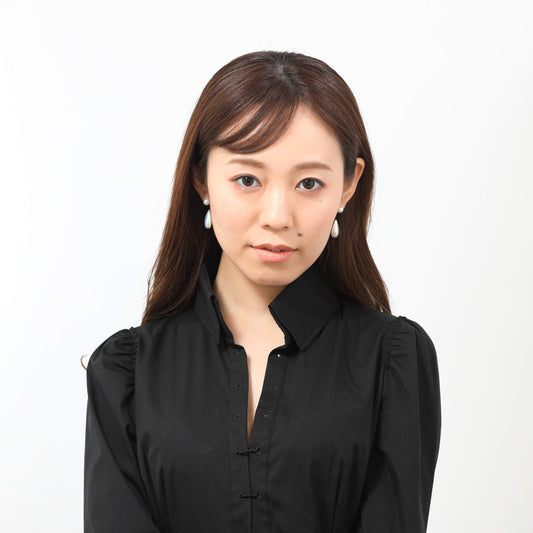 Stylish woman in black shirt posing for a photo, showcasing a Drop Mabe Pearl Piercing.