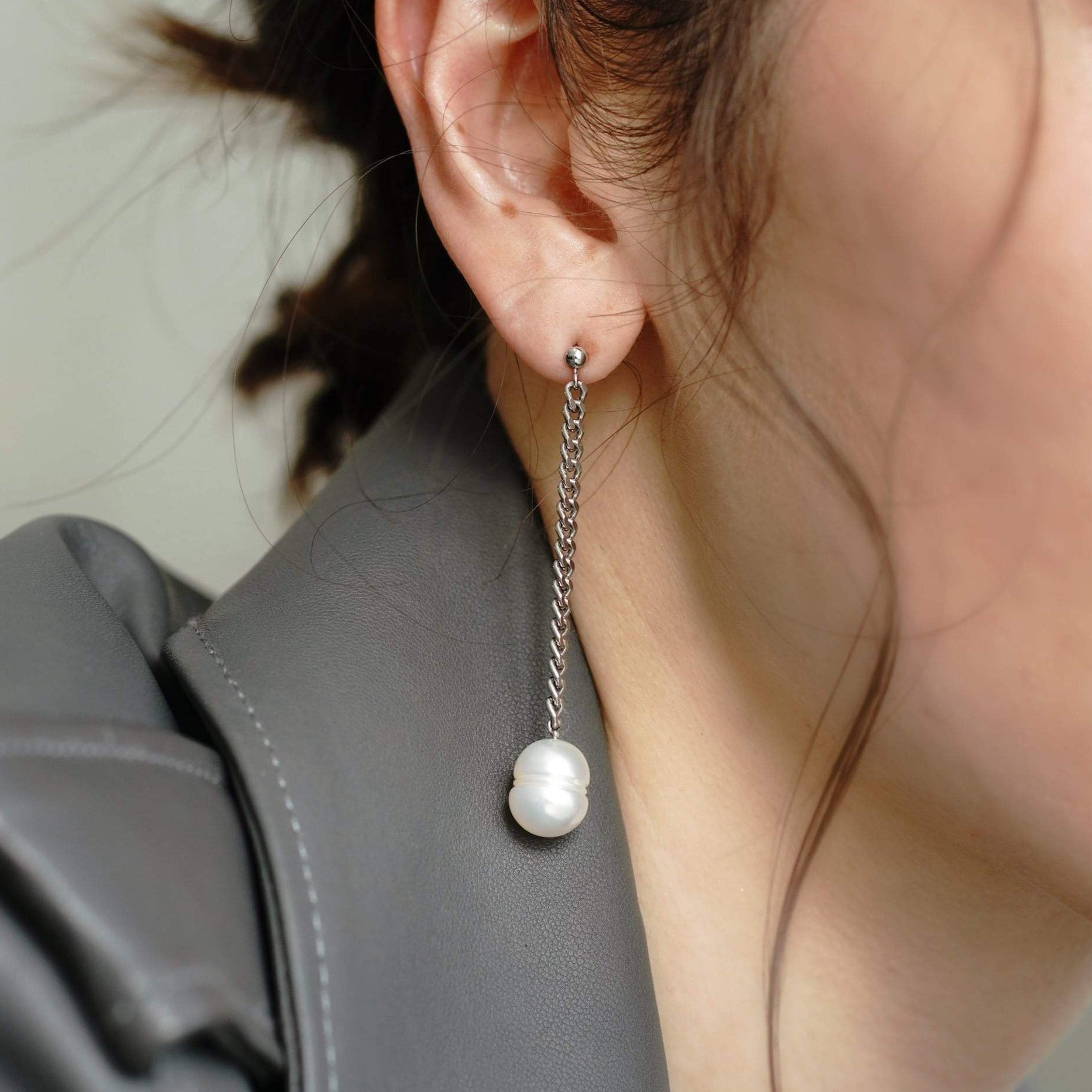 Fashionable lady in leather jacket and earrings with Dangling Pearl Piercing.