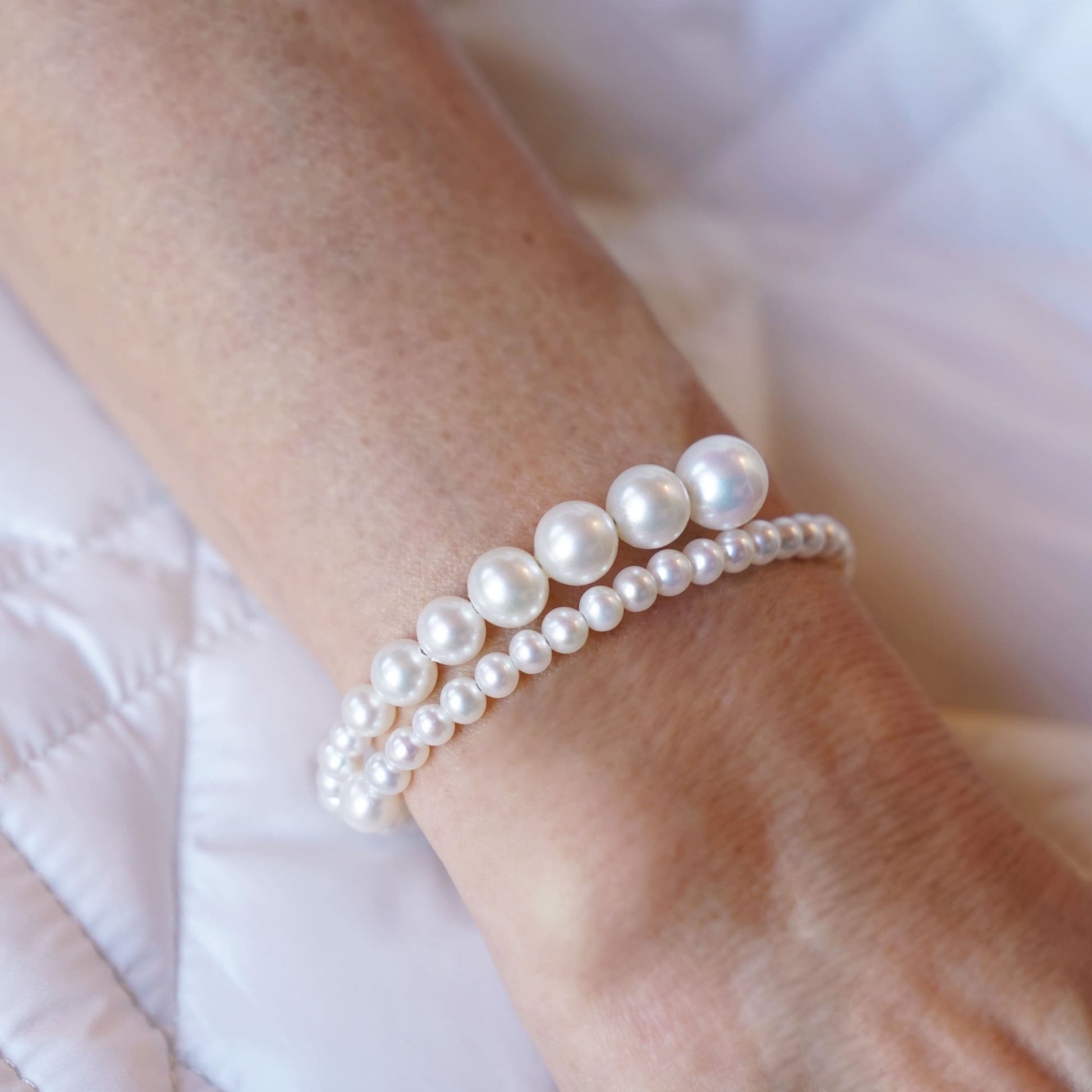 Elegant woman's hand adorned with a Spiral Pearl Bracelet, adding a touch of sophistication and glamour to any outfit.