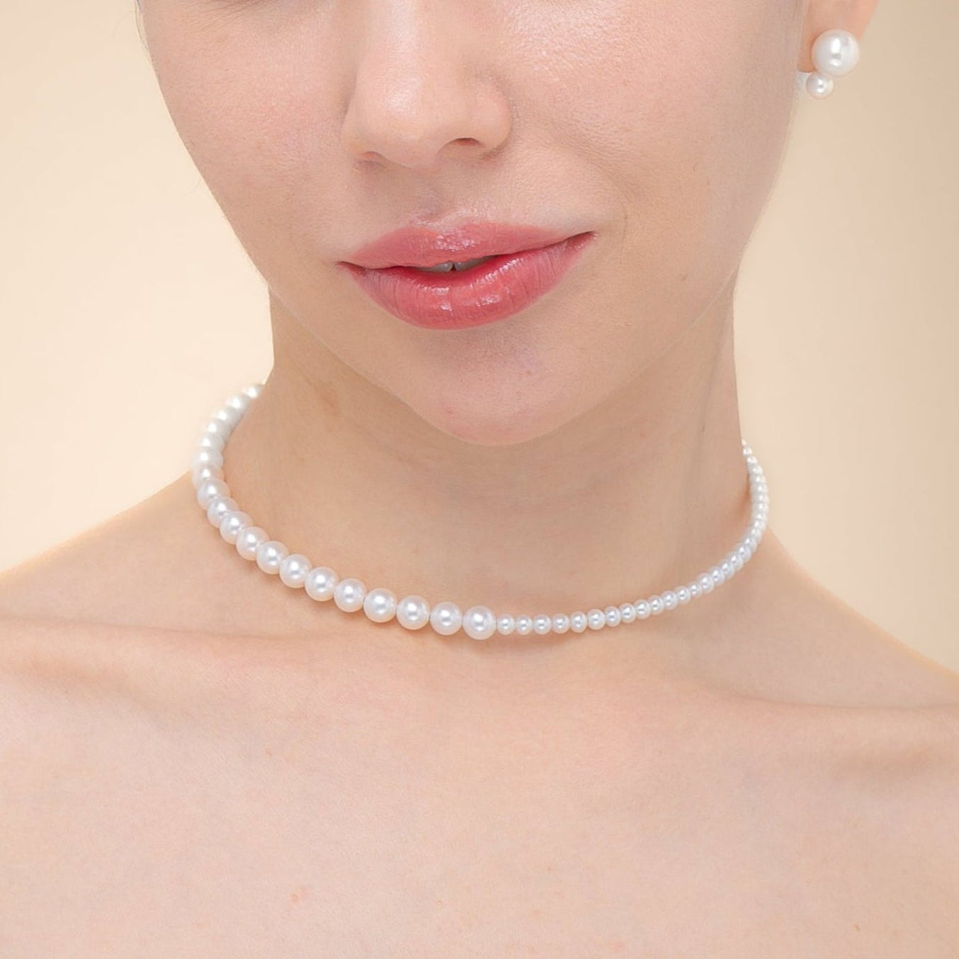 Woman wearing a black dress adorned with a pearl choker necklace, exuding elegance and sophistication.