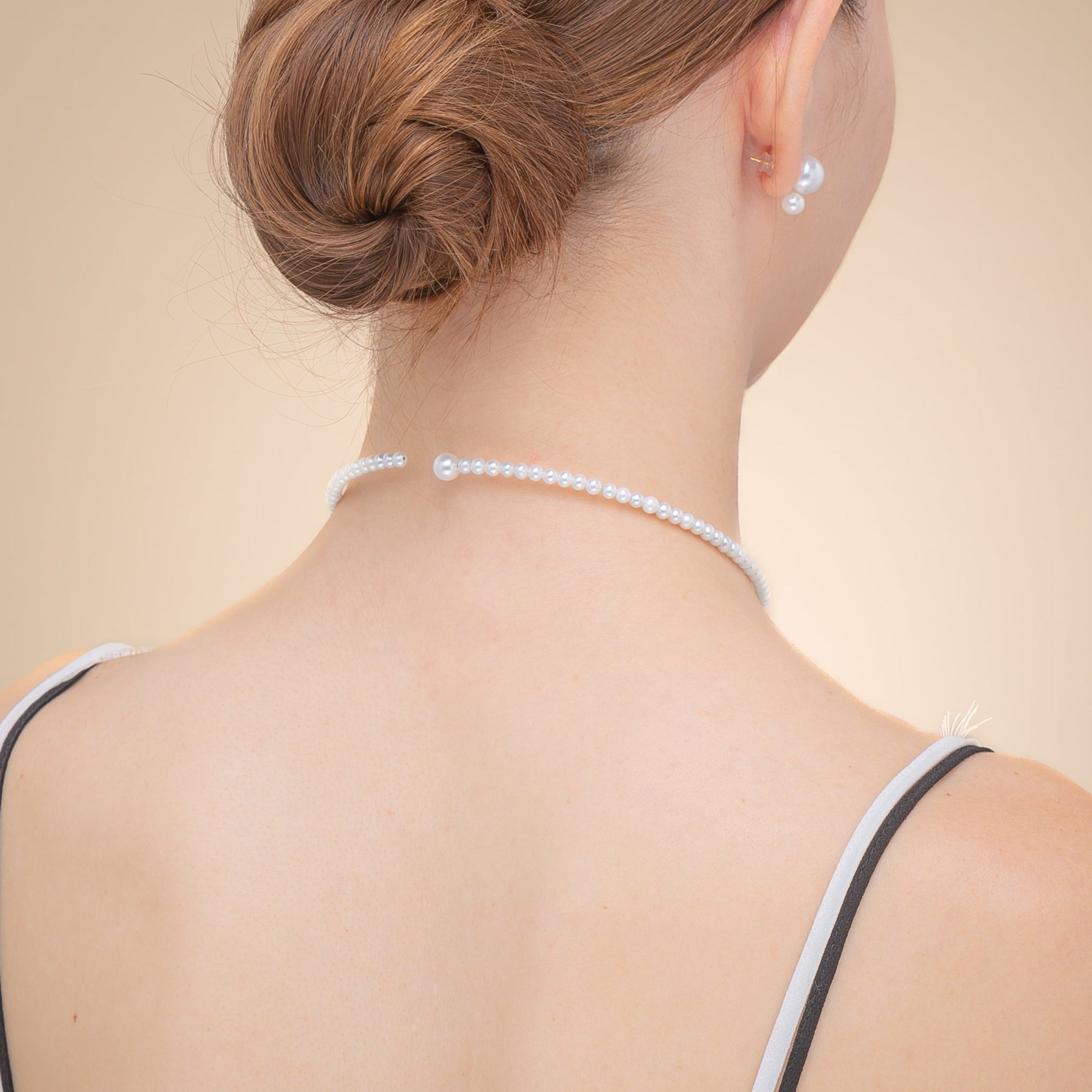 A woman wearing a black dress and a pearl choker necklace, exuding elegance and sophistication.
