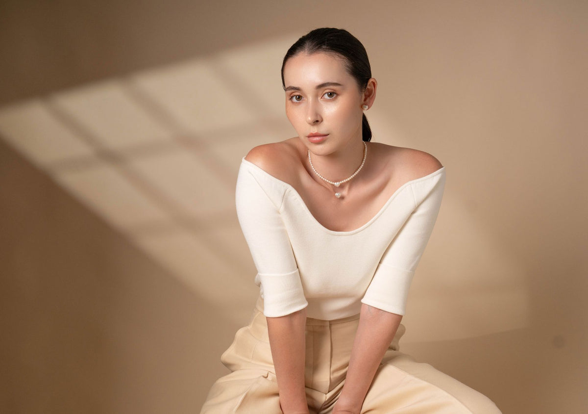 Model in a white off-shoulder top wearing a Pearlish pearl necklace