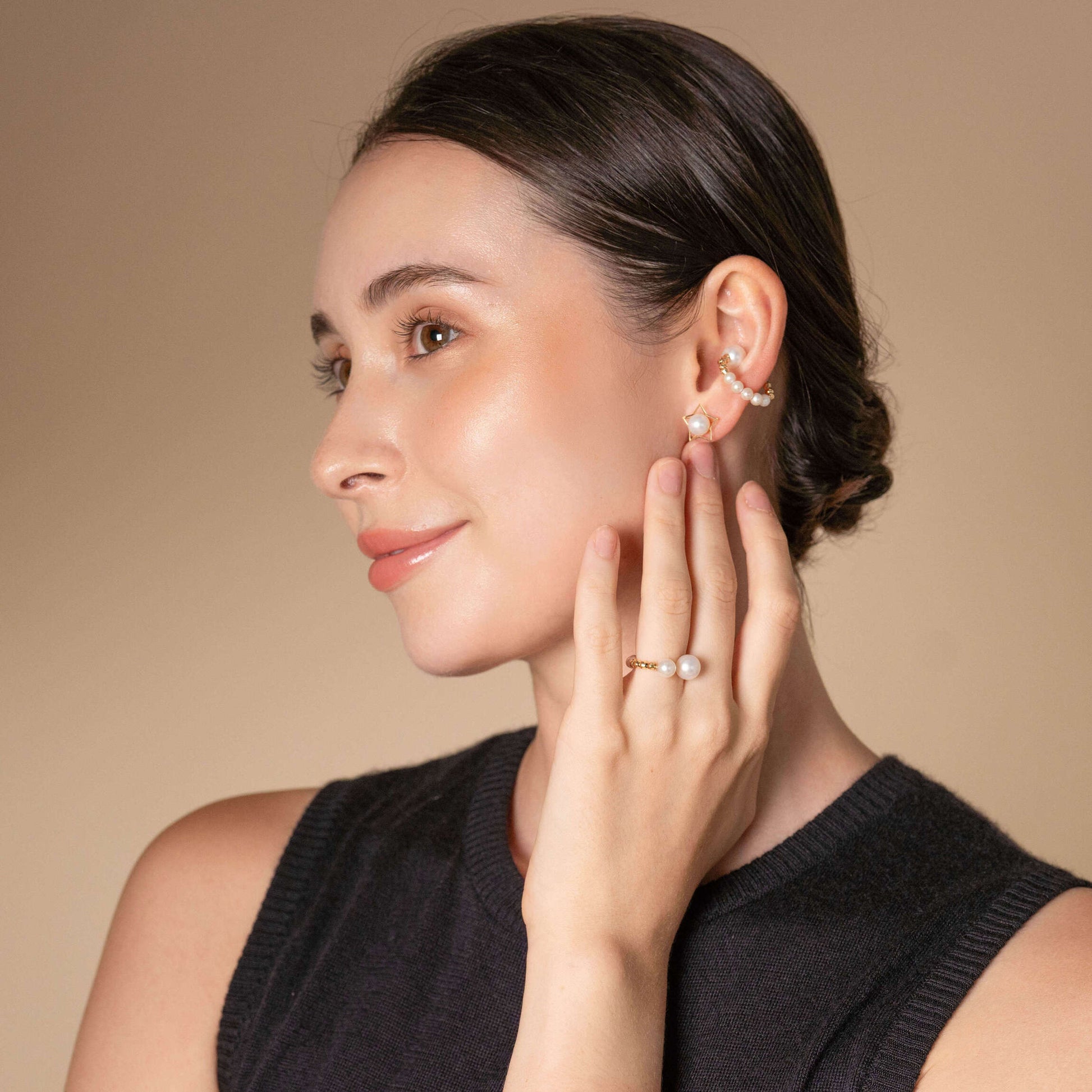 Enhance your elegance with this stunning woman wearing a gold ring and earrings, complemented by a Twin Pearl Earcuff.