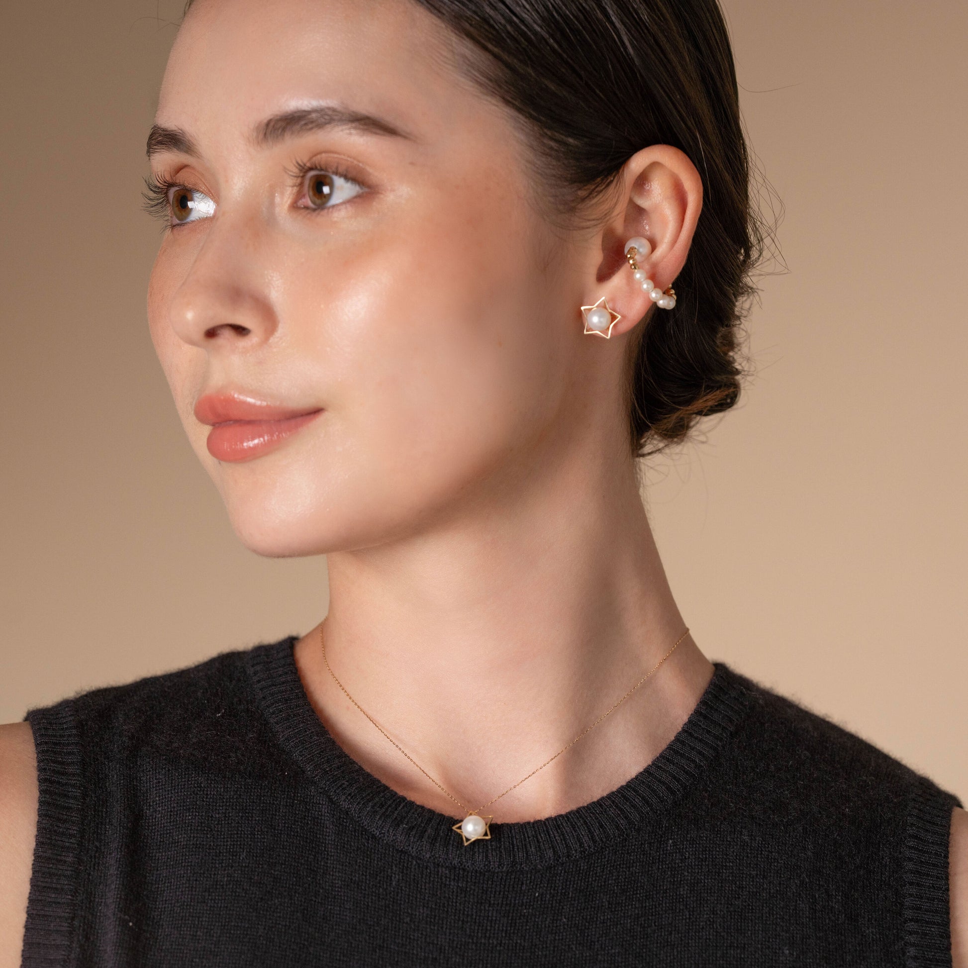 Stylish woman in black top and Star Gold Pearl Piercing earrings exudes elegance.