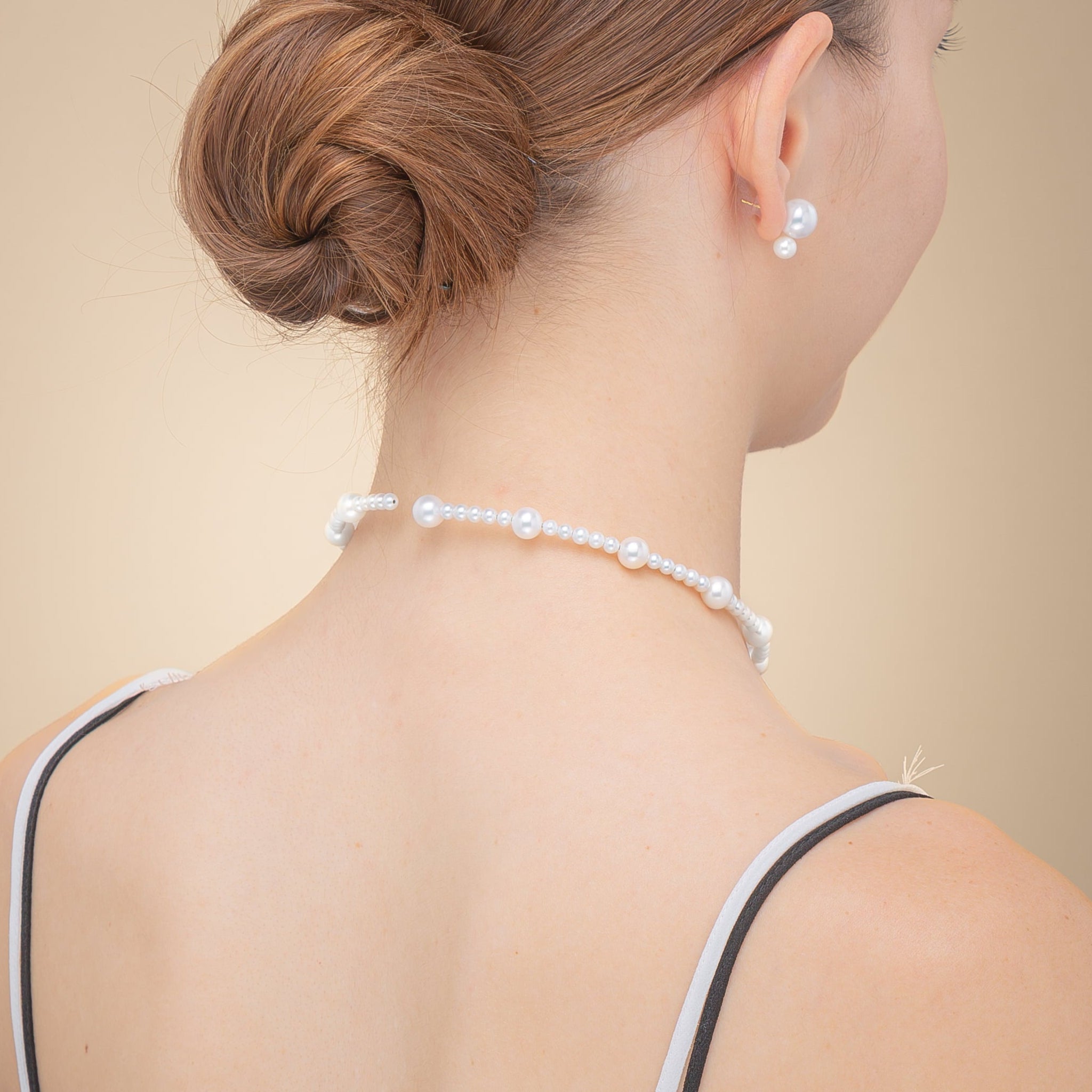 A stylish woman in a black lace top, complemented by a delicate pearl choker necklace, radiating elegance.