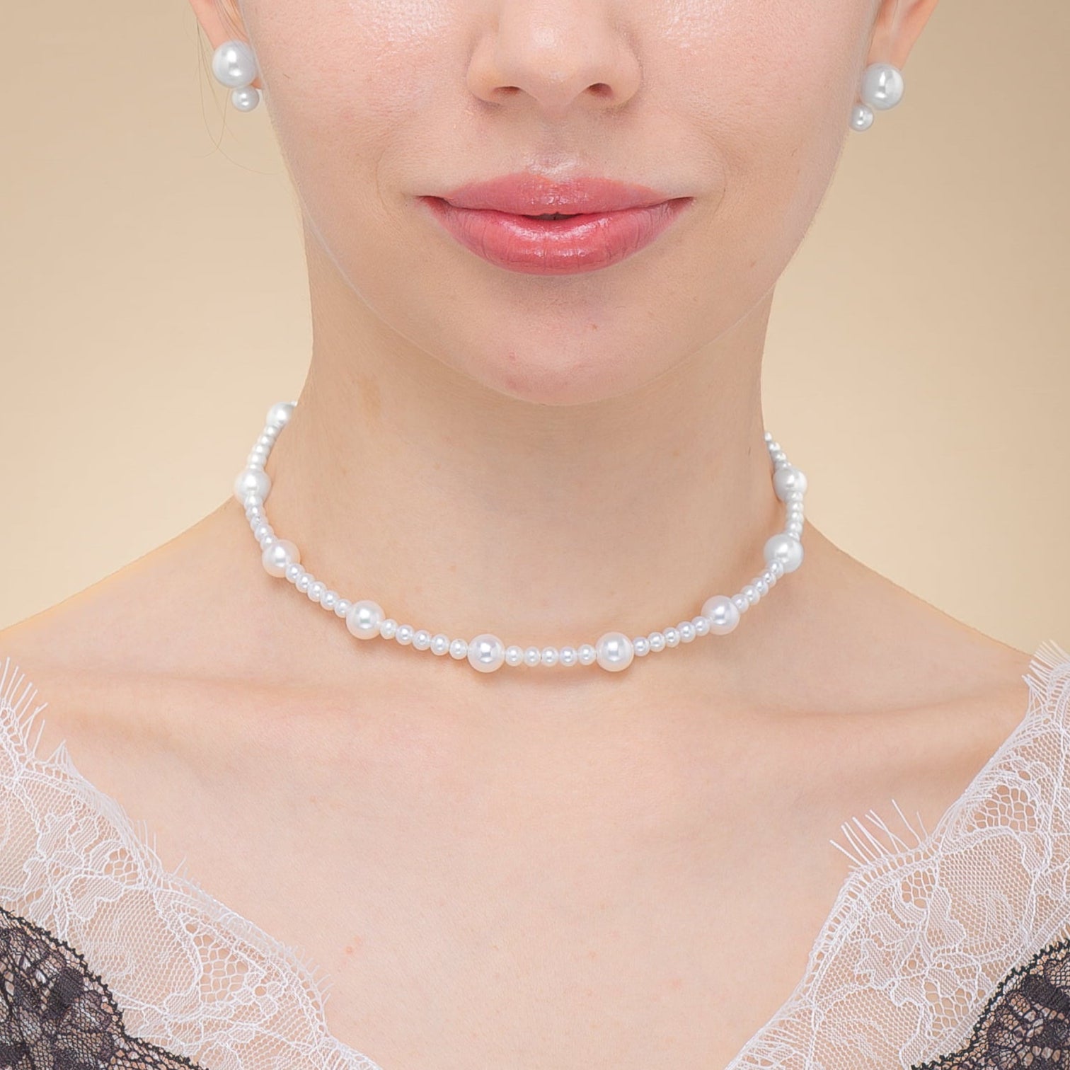 A woman wearing a black lace top and a pearl choker necklace, exuding elegance and style.