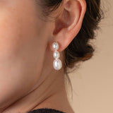 Enhance your style with a chic black top and elegant pearl earrings on a woman. Perfect for any occasion!