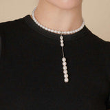 Discover timeless beauty as a woman showcases her sophistication with a pearl necklace and earrings. Complete your ensemble with an alluring Oval Pearl Charm Choker.