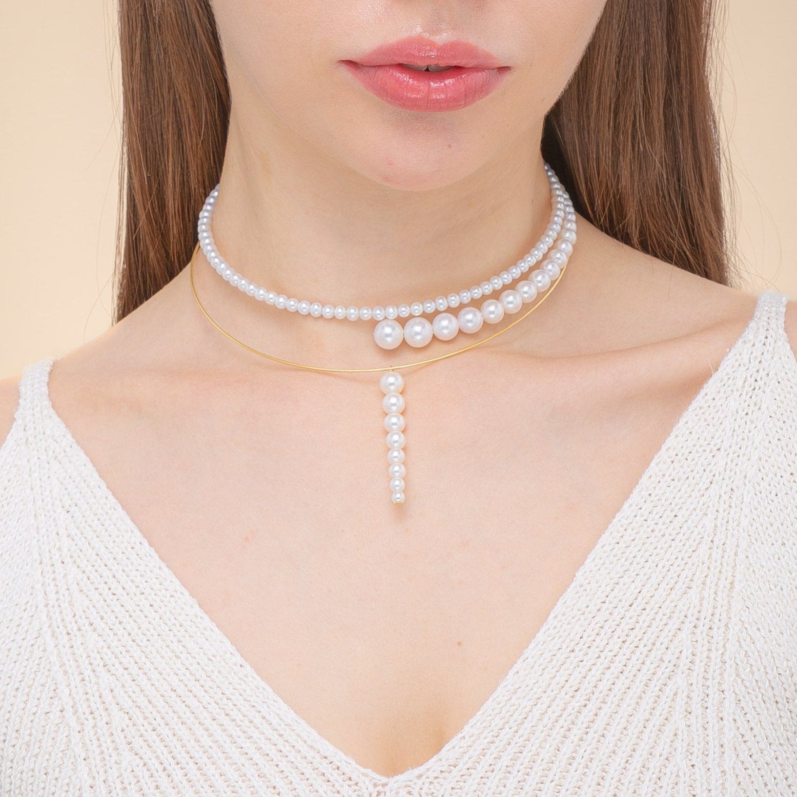 Woman in a chic white top, elegantly accessorized with a freshwater pearl necklace featuring 18K yellow gold accents.
