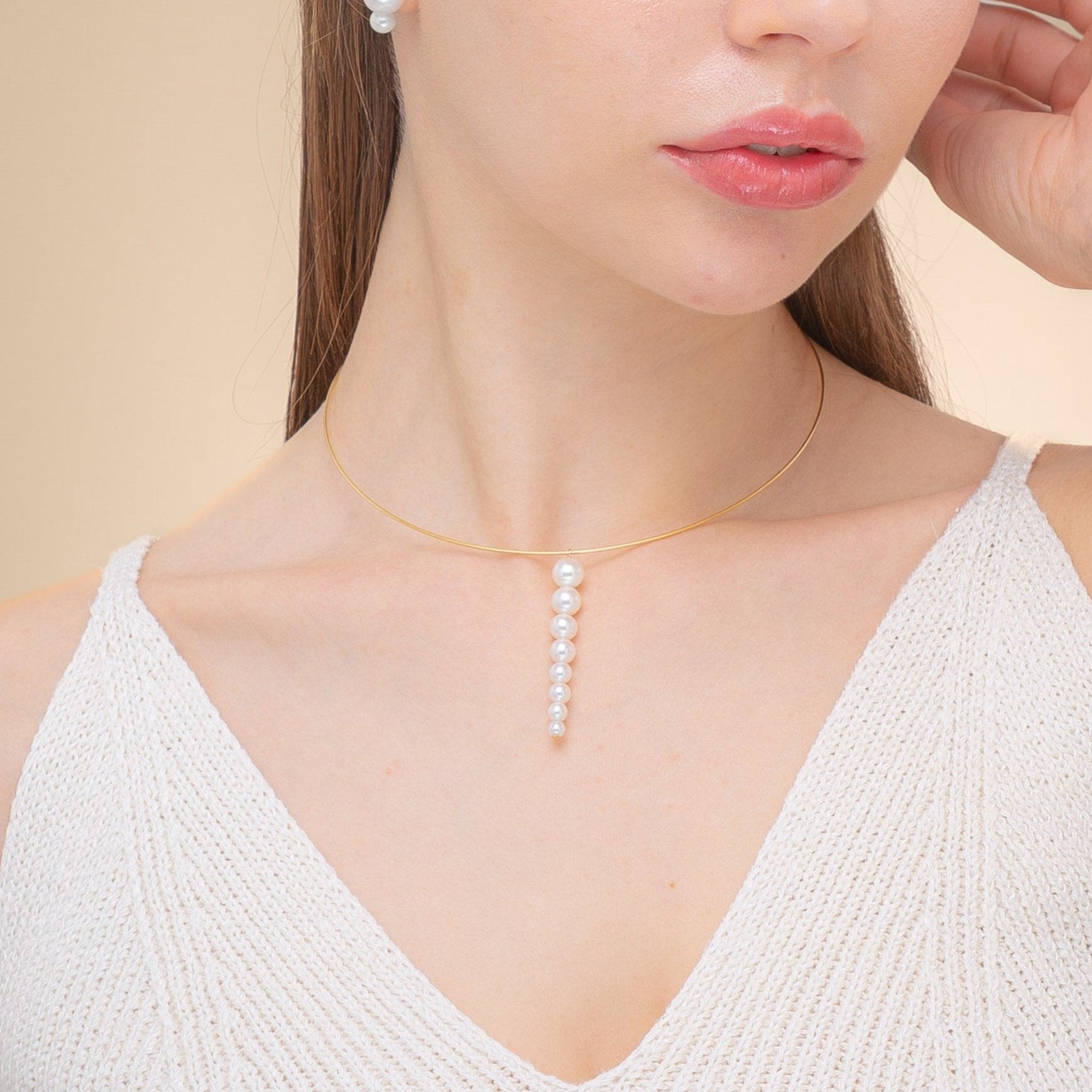 A woman in a white top showcases a stunning necklace of freshwater pearls set in 18K yellow gold.