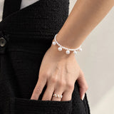 Blair Bracelet on a wrist with the hand in a black tweed pocket, larger freshwater pearls hanging from a row of small pearls