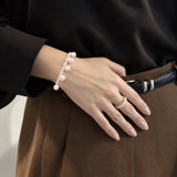 Blair Bracelet worn with a dark blouse and brown trousers, larger freshwater pearls spaced along a row of small pearls on memory wire