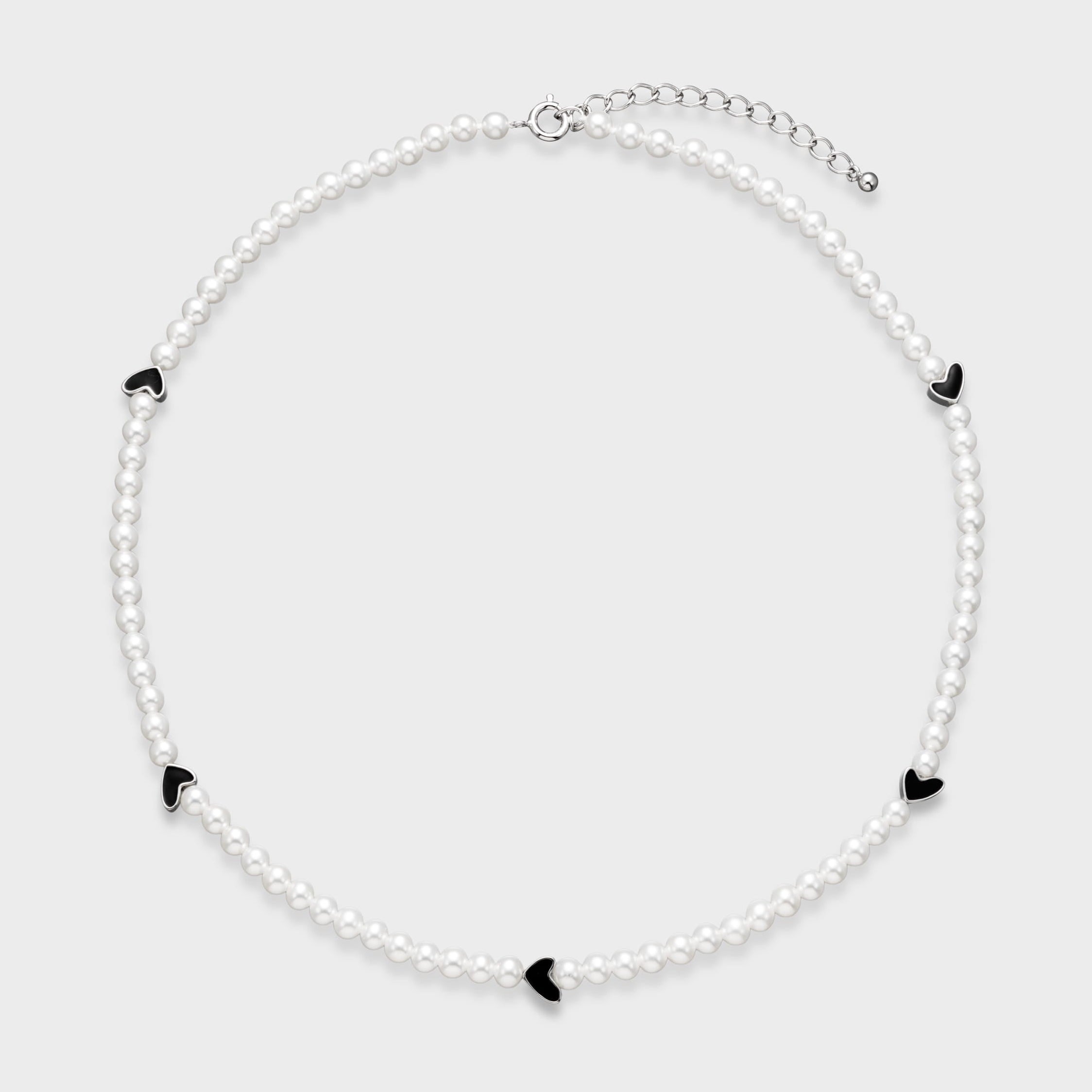 Delicate white pearl necklace with five black enamel heart charms spaced evenly around the strand on a light gray background.