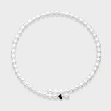 White oval freshwater pearl necklace with small black enamel heart charm accent on a light gray background.