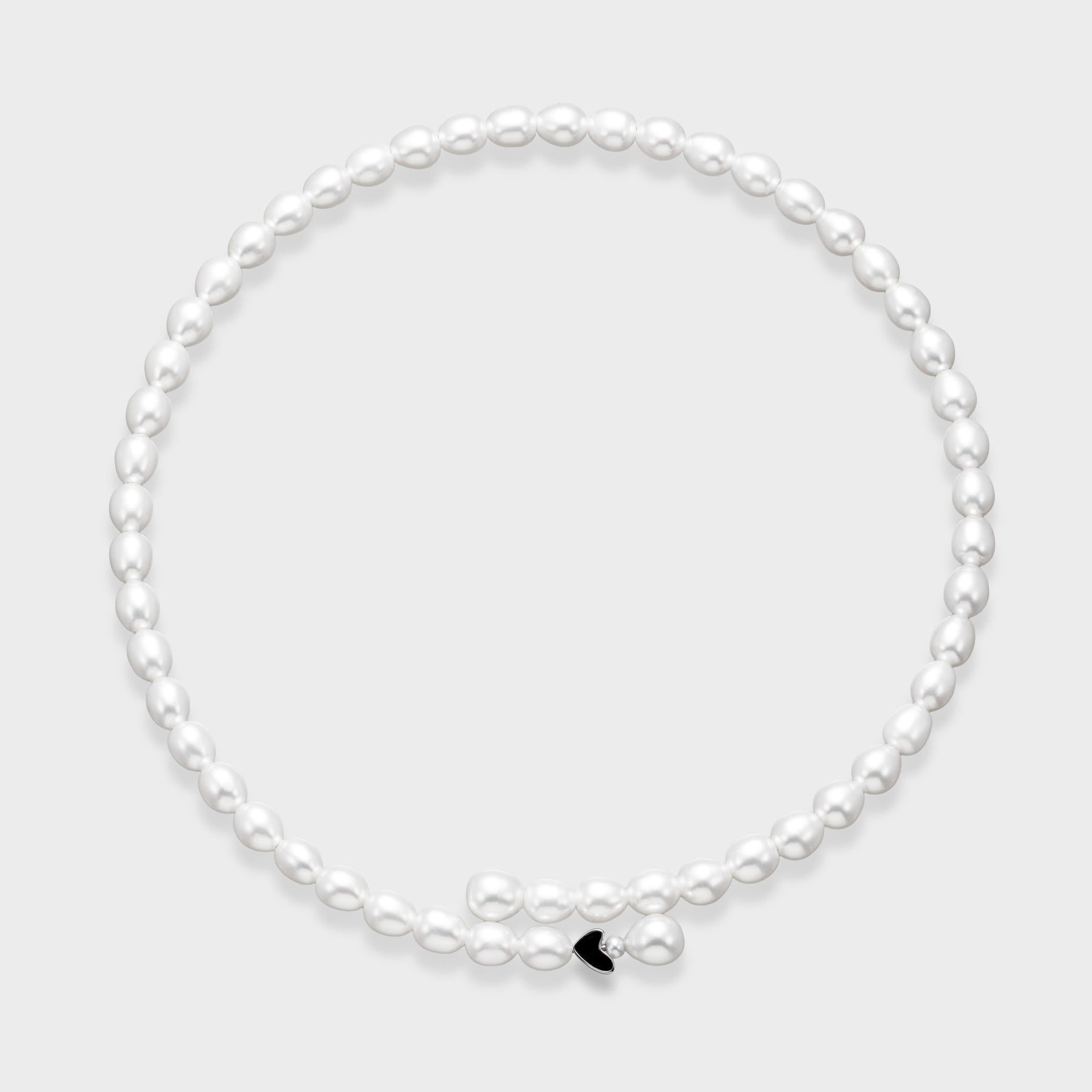 White oval freshwater pearl necklace with small black enamel heart charm accent on a light gray background.