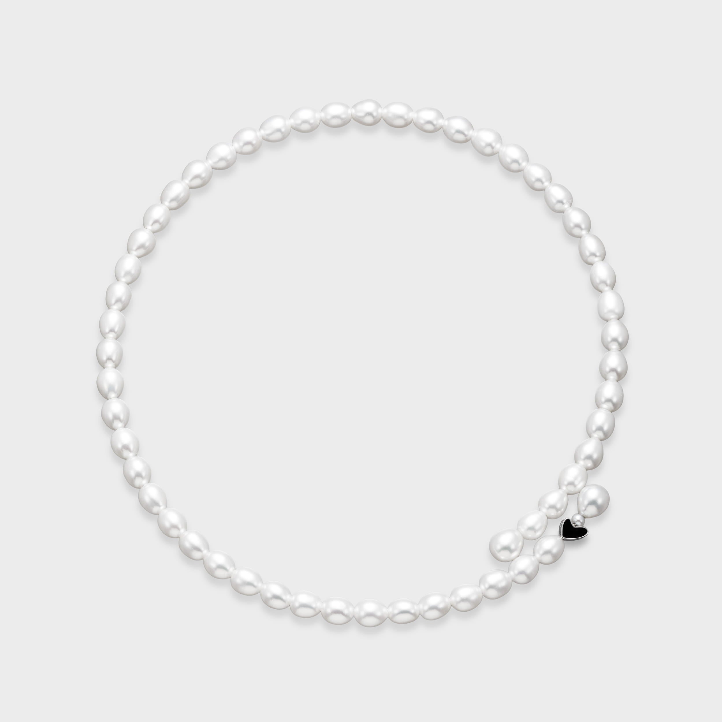 White oval freshwater pearl necklace with small black enamel heart charm accent on a light gray background.