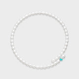 White oval pearl necklace with small turquoise enamel heart charm centered at the front on a light gray background