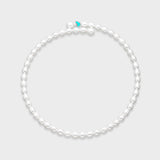 White oval pearl necklace with small turquoise enamel heart charm centered at the front on a light gray background