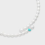 White oval pearl necklace with small turquoise enamel heart charm centered at the front on a light gray background