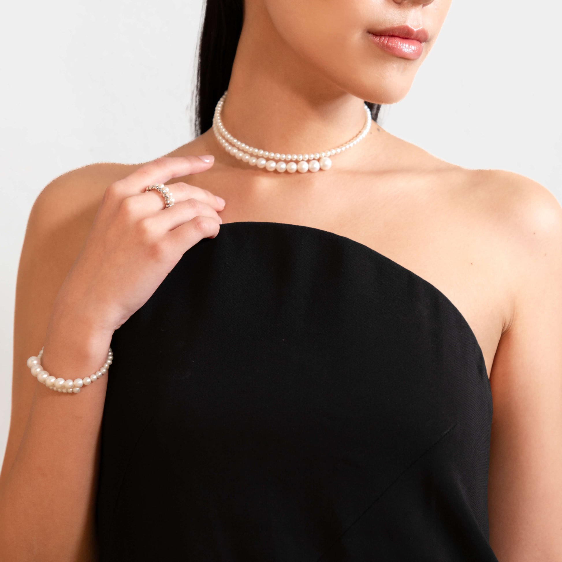 Beautiful model with pearl bracelet, necklace, and ring. Enhance your style today.