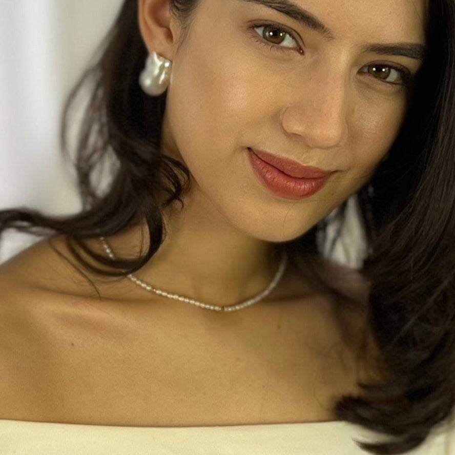 Radiant woman in white shirt looking glamorous with the Amore Necklace in focus.